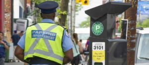 Toronto parking enforcement officer beside a Green P parking machine.
