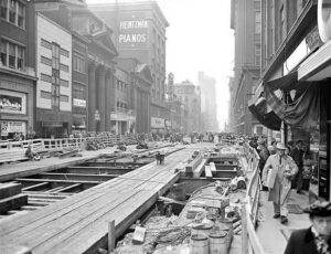 Toronto Yonge Street subway construction in 1950 with workers excavating streetcar tracks near Heintzman Pianos building