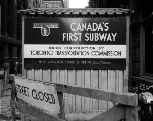 Toronto Transportation Commission sign for Canada’s first subway under construction with street closed barrier in 1950s Toronto