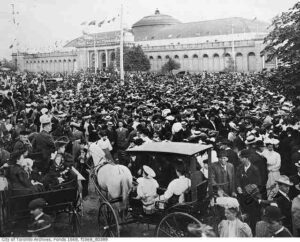 Large crowd at Toronto Exhibition Grounds around 1900 near the Manufacturers Building during the Canadian National Exhibition with horse-drawn carriages and early visitors